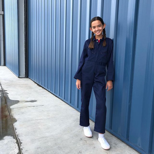 Sophia Hammons's childhood photo in a blue dress and white shoes posing cutely with her two-sided braids.